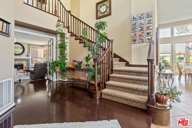 staircase featuring a fireplace, a towering ceiling, and wood-type flooring