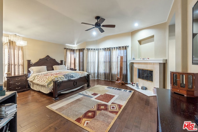 bedroom with a fireplace, dark wood-type flooring, and ceiling fan with notable chandelier