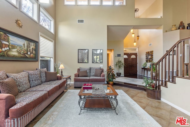 living room featuring plenty of natural light, light tile patterned flooring, and a high ceiling