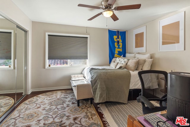 bedroom featuring multiple windows, ceiling fan, a closet, and hardwood / wood-style floors