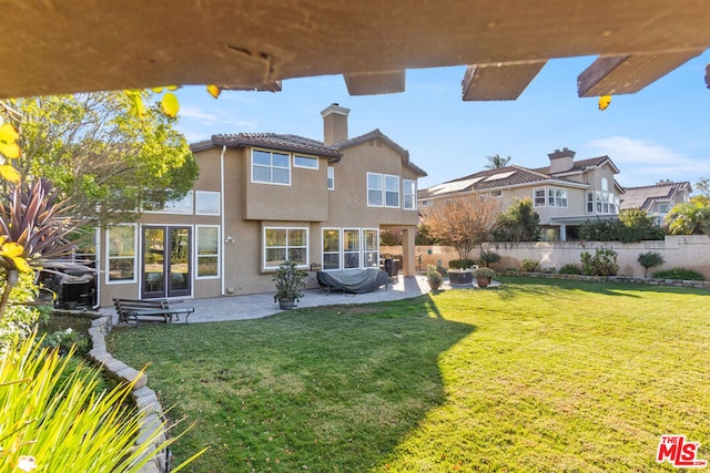 back of property with a yard and a patio