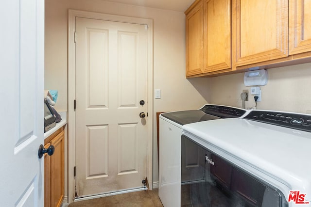 laundry area with separate washer and dryer and cabinets