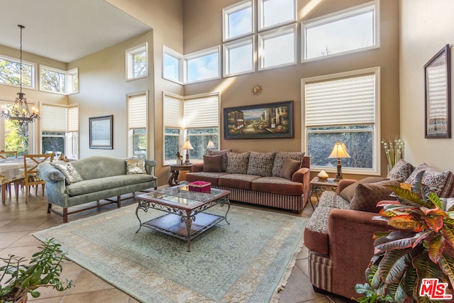 living room featuring a notable chandelier, a towering ceiling, and light tile patterned floors