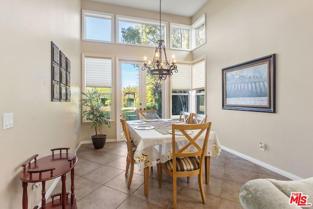 dining room featuring tile patterned floors, a high ceiling, and a notable chandelier