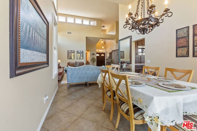 dining space featuring a chandelier, light tile patterned floors, and a high ceiling