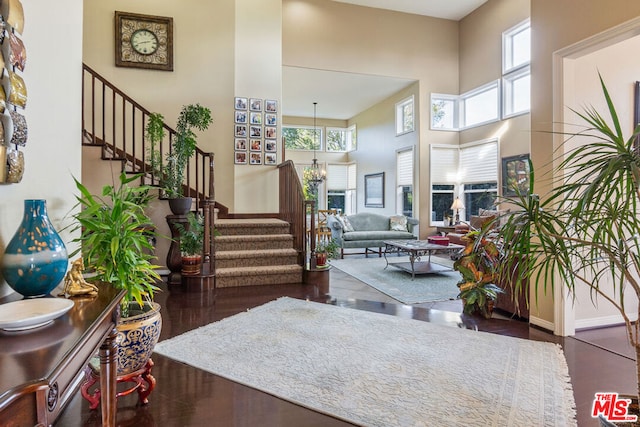 foyer entrance with dark hardwood / wood-style floors, a towering ceiling, and an inviting chandelier