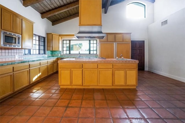 kitchen featuring beamed ceiling, appliances with stainless steel finishes, an island with sink, and wood ceiling