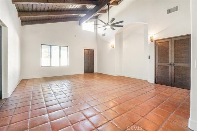 tiled empty room with beamed ceiling, high vaulted ceiling, ceiling fan, and a wealth of natural light