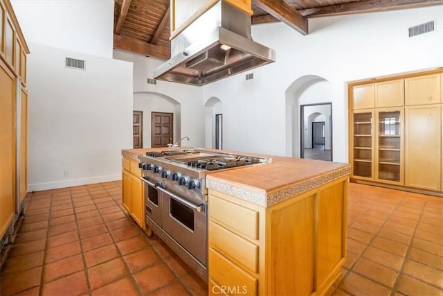 kitchen featuring range with two ovens, high vaulted ceiling, extractor fan, and a kitchen island with sink