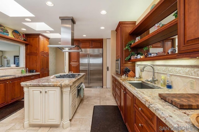 kitchen with a skylight, sink, island range hood, a kitchen island, and appliances with stainless steel finishes