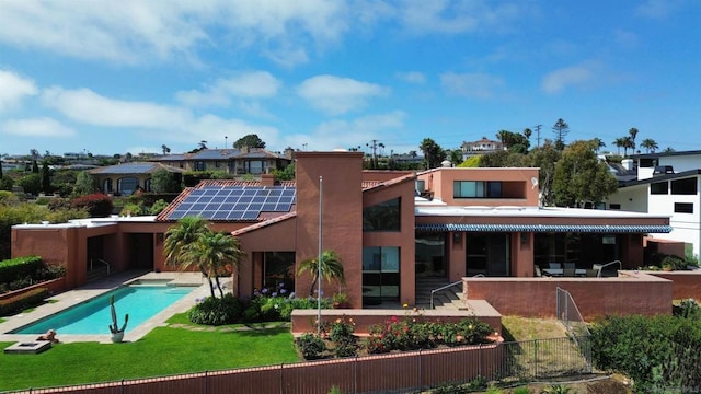 back of property featuring a lawn, a fenced in pool, and solar panels