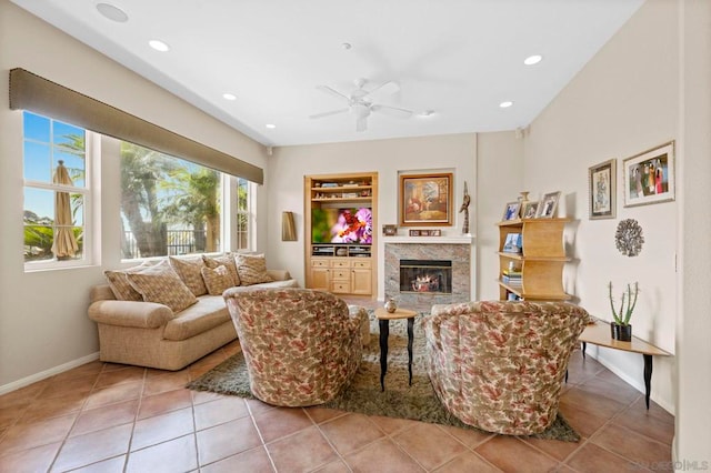 living room featuring ceiling fan, a fireplace, and light tile patterned floors