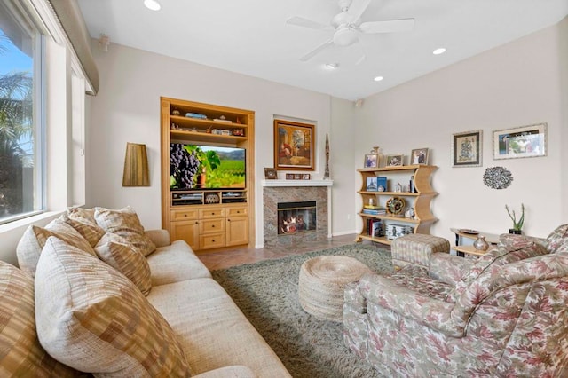 tiled living room featuring ceiling fan, a high end fireplace, and built in shelves