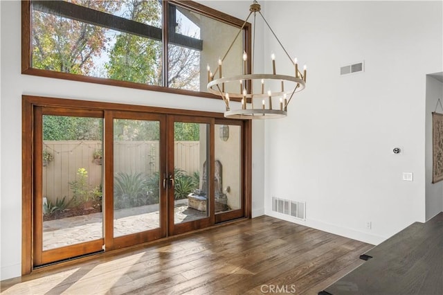 entryway featuring hardwood / wood-style floors, french doors, a chandelier, and a high ceiling