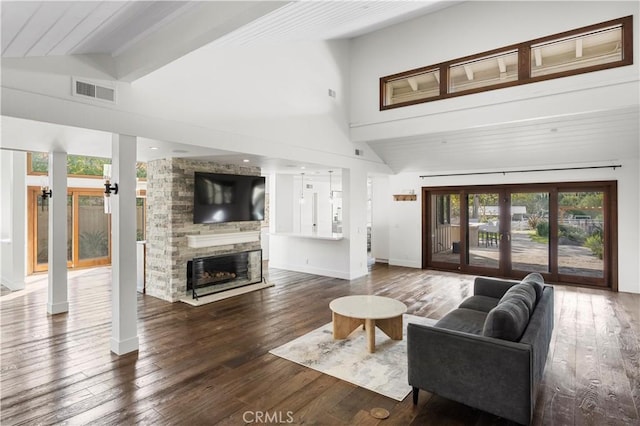 living room featuring dark hardwood / wood-style floors, a fireplace, high vaulted ceiling, and french doors