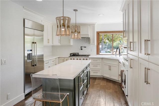 kitchen with white cabinetry, sink, dark wood-type flooring, stainless steel built in fridge, and a kitchen island