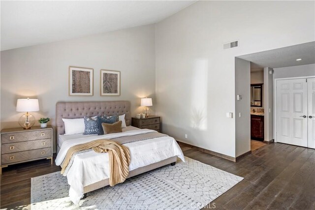 bedroom featuring connected bathroom, dark hardwood / wood-style flooring, and vaulted ceiling