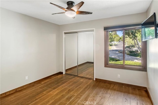 unfurnished bedroom with ceiling fan, a closet, and wood-type flooring