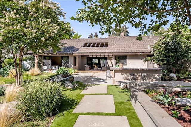 back of property featuring a lawn, a patio area, and an outdoor bar