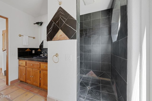 bathroom with tiled shower, vanity, and tile patterned floors