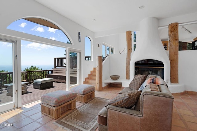 living room featuring a large fireplace, a healthy amount of sunlight, a water view, and light tile patterned floors