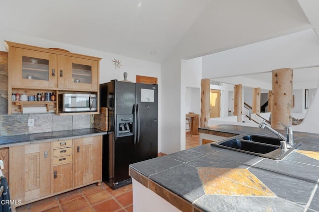 kitchen featuring sink, vaulted ceiling, tasteful backsplash, light tile patterned flooring, and black fridge with ice dispenser