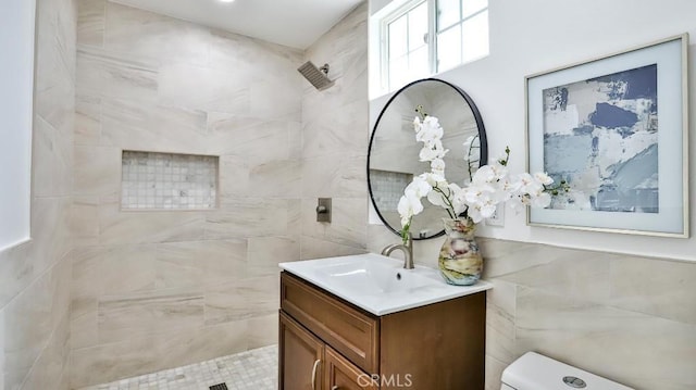 bathroom featuring vanity, toilet, and a tile shower