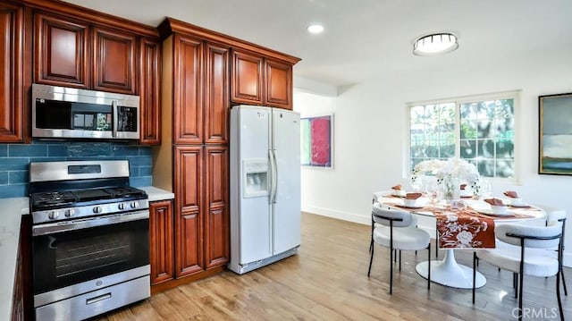 kitchen featuring light wood-type flooring, decorative backsplash, and appliances with stainless steel finishes