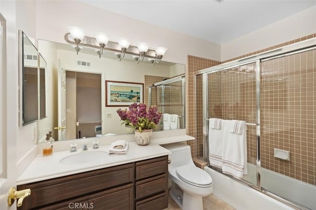 full bathroom featuring shower / bath combination with glass door, tile patterned floors, vanity, and toilet