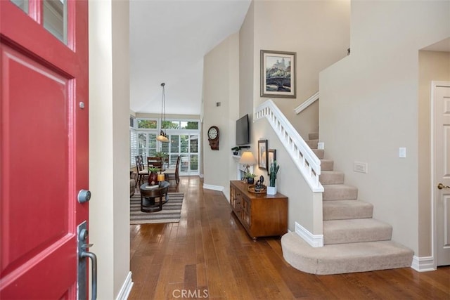 entryway with a towering ceiling and dark hardwood / wood-style floors