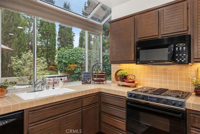 kitchen featuring tasteful backsplash, tile counters, black appliances, and sink