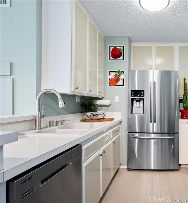 kitchen featuring a textured ceiling, stainless steel appliances, white cabinetry, and sink