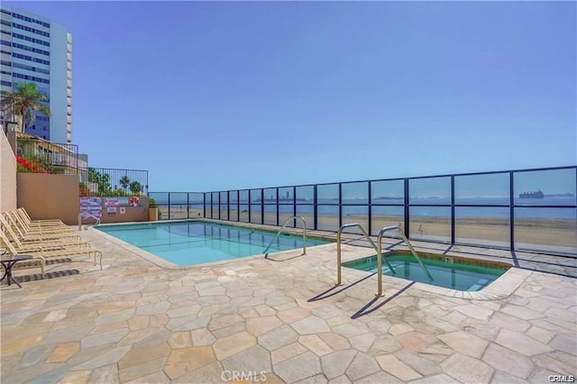 view of pool featuring a community hot tub, a patio, and a water view