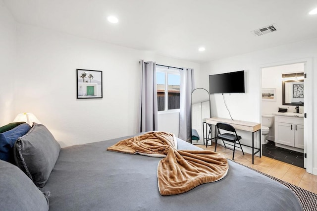 bedroom with hardwood / wood-style floors and ensuite bath