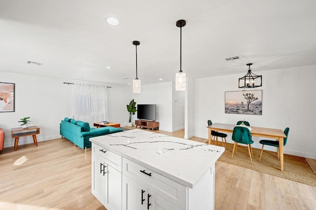 kitchen featuring light hardwood / wood-style floors, hanging light fixtures, light stone countertops, a chandelier, and white cabinets