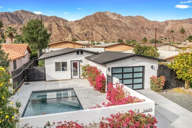 view of front of house with a patio area, a mountain view, a fenced in pool, and a garage