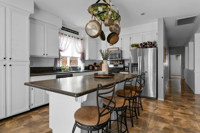 kitchen with white cabinets, a kitchen breakfast bar, sink, appliances with stainless steel finishes, and a kitchen island