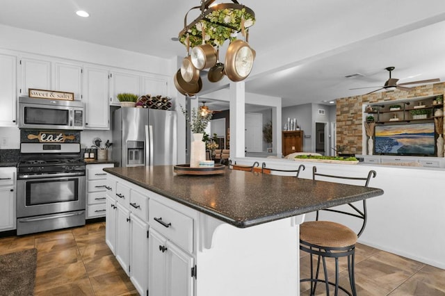 kitchen featuring appliances with stainless steel finishes, a kitchen island, white cabinetry, and a breakfast bar area