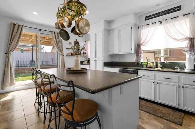 kitchen with a breakfast bar, a center island, white cabinetry, and a healthy amount of sunlight