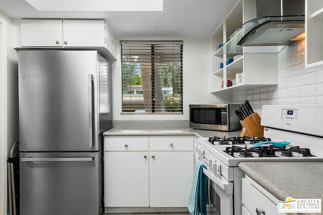 kitchen featuring tasteful backsplash, white cabinetry, stainless steel appliances, and wall chimney range hood