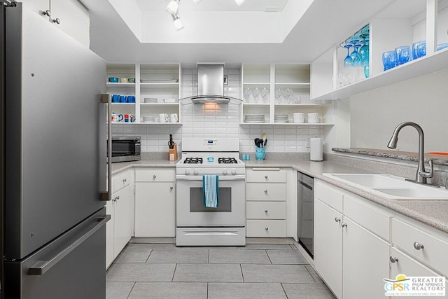 kitchen featuring backsplash, white cabinets, wall chimney range hood, sink, and appliances with stainless steel finishes