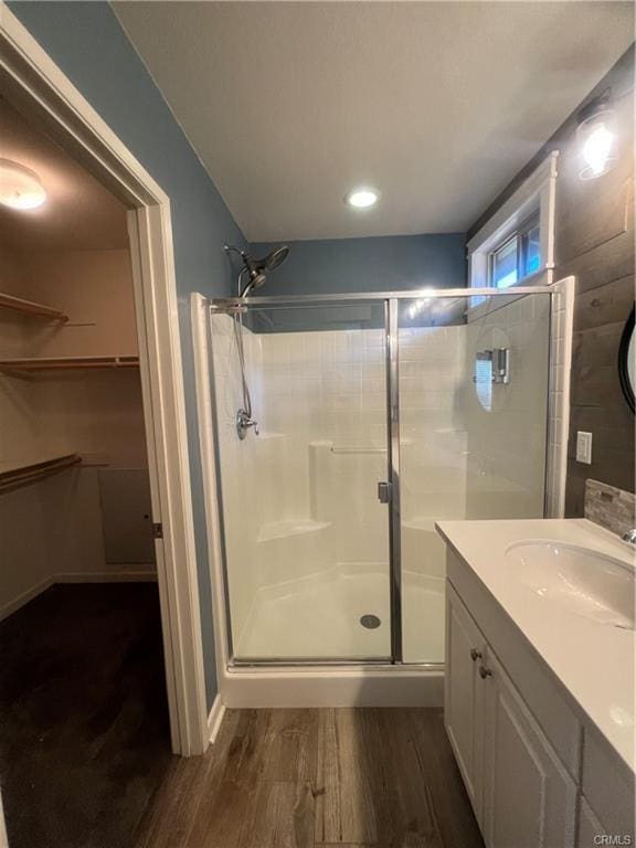 bathroom with hardwood / wood-style floors, vanity, and a shower with door