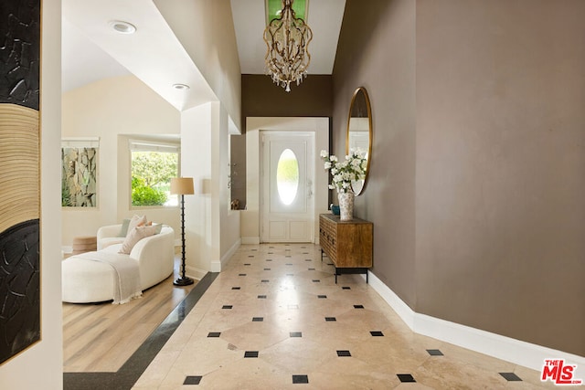 entryway featuring light hardwood / wood-style floors, lofted ceiling, and a chandelier