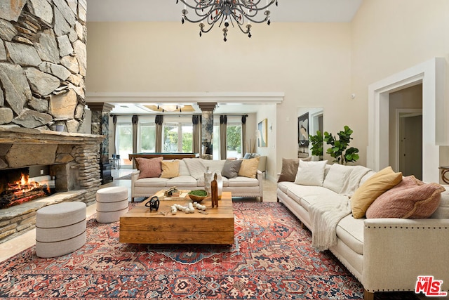 living room with a towering ceiling, a fireplace, and a chandelier