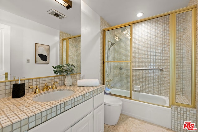 full bathroom featuring tile patterned floors, vanity, enclosed tub / shower combo, and toilet