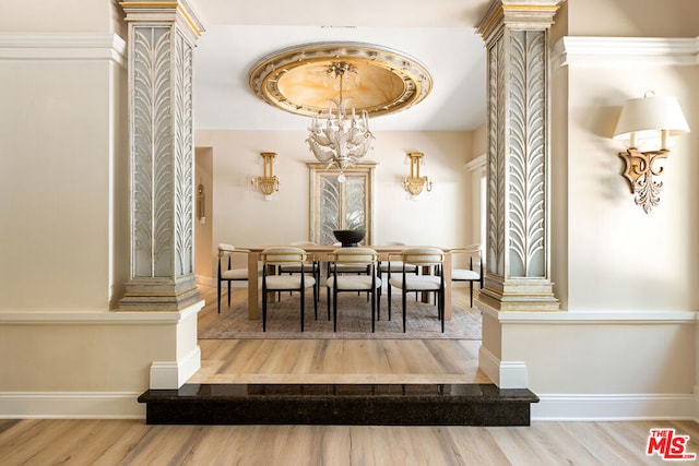 dining space featuring ornate columns, hardwood / wood-style floors, and a notable chandelier