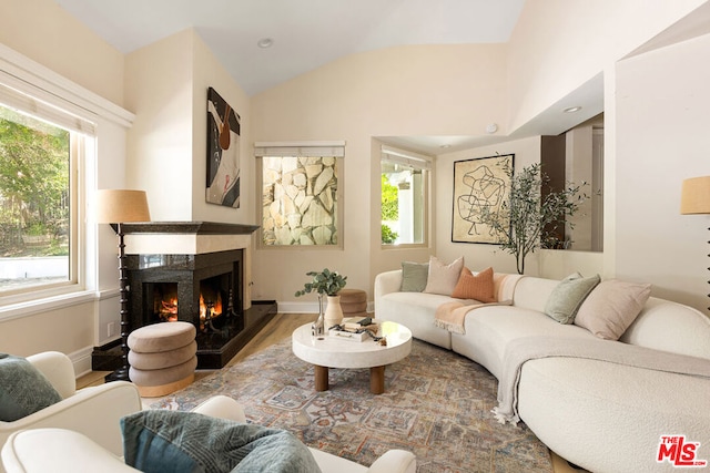 living room featuring a high end fireplace, lofted ceiling, and hardwood / wood-style flooring