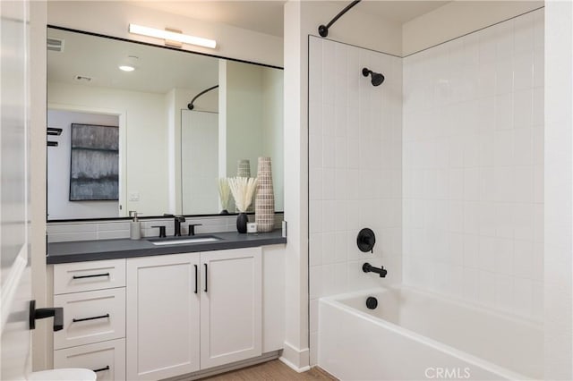 bathroom featuring hardwood / wood-style floors, vanity, and tiled shower / bath