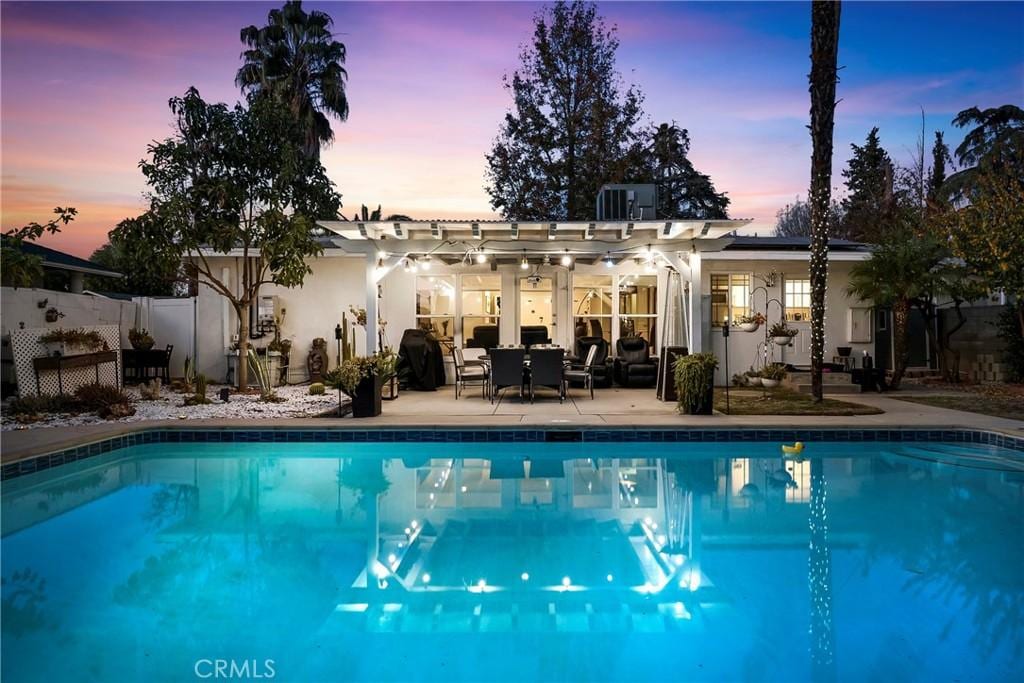 pool at dusk featuring central AC and a patio area