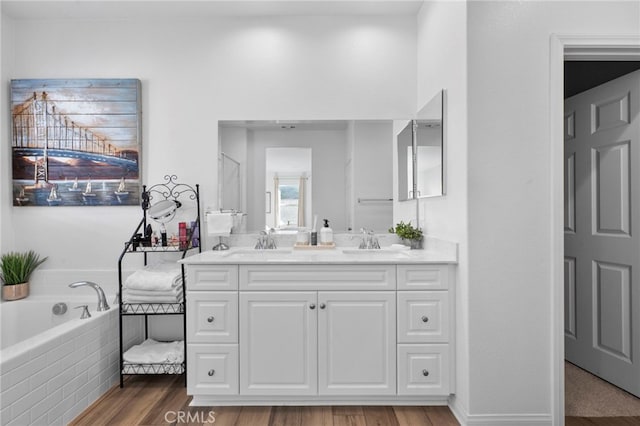 bathroom featuring tiled tub, vanity, and hardwood / wood-style floors